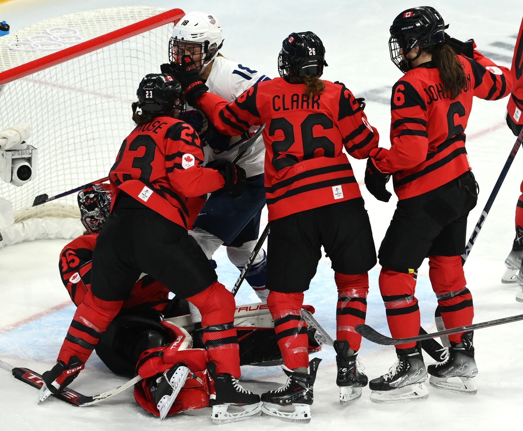 Američanka Jesse Compherová ve střetu s kanadskými hokejistkami ve finále ZOH 2022.