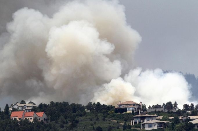 Smoke billows near houses in a mountain subdivision, west of Colorado Springs June 24, 2012. A fast-growing wildfire has forced thousands of residents from homes in Colorado Springs, Colorado, and nearby communities as firefighters struggled on Sunday to contain out-of-control and wind-stoked blazes in several western U.S. states. REUTERS/Rick Wilking (UNITED STATES - Tags: DISASTER ENVIRONMENT) Published: Čer. 24, 2012, 8:23 odp.