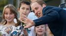 Britain's Prince William is greeted by children bearing gifts during his visit to the &quot;Three Sisters&quot; rock formation with his wife Catherine, the Duchess of Cam