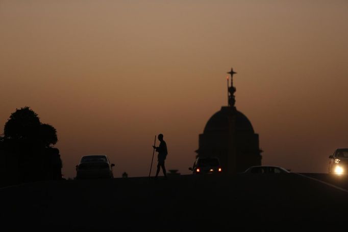 Mahesh Chaturvedi, 63, who dresses up like Mahatma Gandhi, is silhouetted against India's presidential palace Rashtrapati Bhavan in New Delhi October 4, 2012. Chaturvedi says that the soul of Gandhi resides in him and he has been sent to continue the work of Father of the Nation. After his self proclaimed transformation in 2002 as Gandhi, Chaturvedi has been travelling extensively and plays up to his startling resemblance to Gandhi at protests and demonstrations. Picture taken October 4, 2012. REUTERS/Mansi Thapliyal (INDIA - Tags: SOCIETY) Published: Lis. 26, 2012, 4:01 dop.