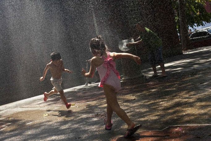 Children cool off by running through water sprinklers during a hot day in New York, August 4, 2012. Temperatures are expected to reach about 93 degrees Fahrenheit (34 Celcius) today in New York. REUTERS/Andrew Burton (UNITED STATES - Tags: ENVIRONMENT) Published: Srp. 4, 2012, 7:20 odp.