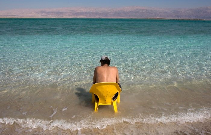 Turista sedí na židli v Mrtvém moři