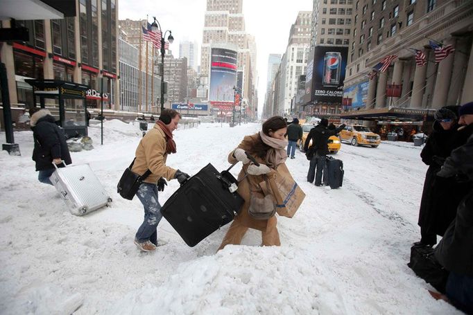 Dívky se snaží přetáhnout svá zavazadla přes závěje sněhu na Sedmé avenue u nádraží Penn Station, New York.