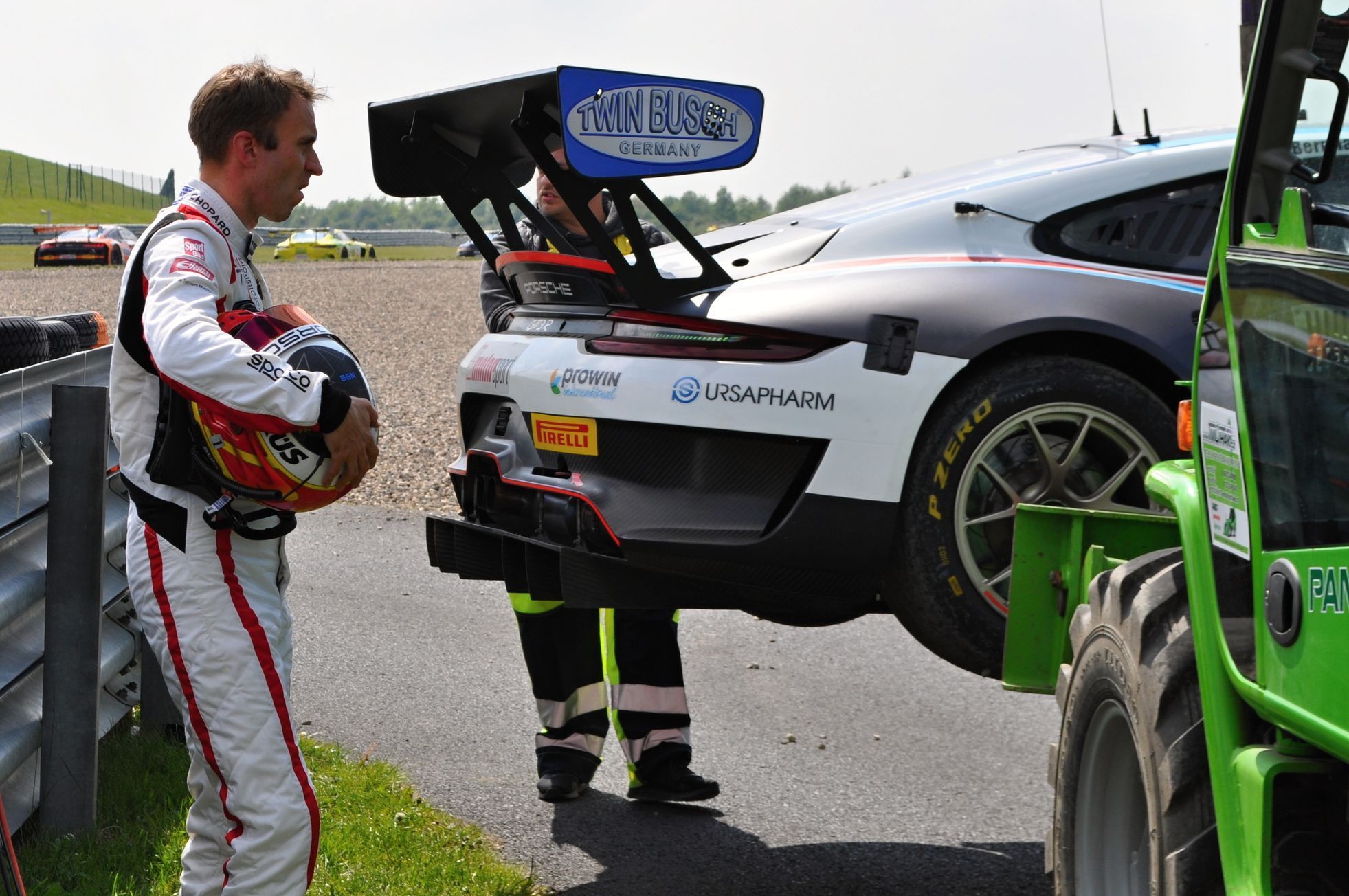 Timo Bernhard sleduje, jak mostečtí pořadatelé odvážejí jeho rozbité Porsche během závodu ADAC GT Masters 2019