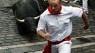 A runner sprints as a Fuente Ymbro fighting bull falls at the Estafeta corner during the fifth running of the bulls of the San Fermin festival in Pamplona July 11, 2012. Several runners suffered light injuries in a run that lasted three minutes and twelve seconds, according to local media. REUTERS/Susana Vera (SPAIN - Tags: SOCIETY ANIMALS) Published: Čec. 11, 2012, 8:56 dop.