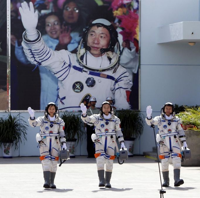 Chinese astronauts Jing Haipeng (C), Liu Wang (R) and Liu Yang, China's first female astronaut, wave in front of a picture of the first astronaut Yang Liwei during a departure ceremony at Jiuquan Satellite Launch Center, Gansu province, June 16, 2012. China will send its first woman into outer space this week, prompting a surge of national pride as the rising power takes its latest step towards putting a space station in orbit within the decade. Liu Yang, a 33-year-old fighter pilot, will join two other astronauts aboard the Shenzhou 9 spacecraft when it lifts off from a remote Gobi Desert launch site on Saturday evening. REUTERS/Jason Lee (CHINA - Tags: SCIENCE TECHNOLOGY) Published: Čer. 16, 2012, 8:48 dop.