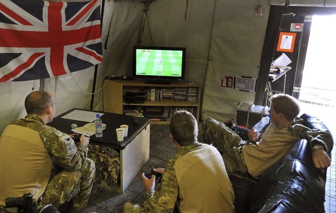 Britain's Prince Harry (R) relaxes with fellow Apache crew members as they play a computer soccer game at Camp Bastion, southern Afghanistan in this photograph taken November 1, 2012, and released January 21, 2013. The Prince, who is serving as a pilot/gunner with 662 Squadron Army Air Corps, is on a posting to Afghanistan that runs from September 2012 to January 2013. Photograph taken November 1, 2012. REUTERS/John Stillwell/Pool (AFGHANISTAN - Tags: MILITARY POLITICS SOCIETY MEDIA ROYALS CONFLICT) Published: Led. 21, 2013, 8:55 odp.