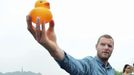 Dutch artist Florentijn Hofman holds up a Rubber Duck on the bank of the West Lake to look for a proper site for the installation and display of the duck in Hangzhou city, east Chinas Zhejiang province, 26 June 2013. Dutch artist Florentijn Hofman, known for playful urban installations, such as the Rubber Duck, visited eastern Chinese tourism city of Hangzhou on Wednesday (26 June 2013) to look for a proper site to install and display the duck. He toured around the West Lake and took pictures to seek the best location for his installation. It is estimated that the Rubber Duck will come to the West Lake as an attraction in the fourth quarter of this year.(Imaginechina via AP Images)