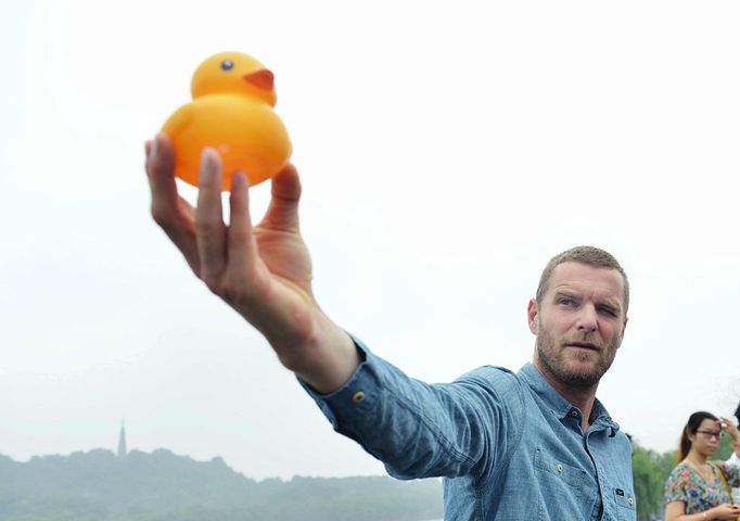 Dutch artist Florentijn Hofman holds up a Rubber Duck on the bank of the West Lake to look for a proper site for the installation and display of the duck in Hangzhou city, east Chinas Zhejiang province, 26 June 2013. Dutch artist Florentijn Hofman, known for playful urban installations, such as the Rubber Duck, visited eastern Chinese tourism city of Hangzhou on Wednesday (26 June 2013) to look for a proper site to install and display the duck. He toured around the West Lake and took pictures to seek the best location for his installation. It is estimated that the Rubber Duck will come to the West Lake as an attraction in the fourth quarter of this year.(Imaginechina via AP Images)