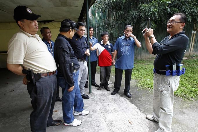 Jaime "Jimmy" Santiago (R), a lower court judge in Manila, with his fellow court judges and their security officer shows his service pistol before their shooting practice at a police firing range in Manila March 6, 2013. Santiago, a former police officer who headed a special weapons and tactics (SWAT) unit, favours arming Filipino judges to protect themselves from disgruntled litigants who can't accept decisions and criminal syndicates whose members were sent to jail. There had been cases of shootings inside courtrooms. In photo is Judge court Emilio Legazpi III (L), Judge court Armando Yanga (2nd from L) and Judge court Jose Lorenzo Dela Rosa (3rd from L). REUTERS/Romeo Ranoco (PHILIPPINES - Tags: POLITICS CRIME LAW) Published: Dub. 4, 2013, 11:08 dop.