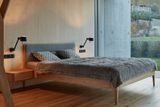Jednoduchému prostoru dominuje světlé dřevo a postel s čalouněním.
