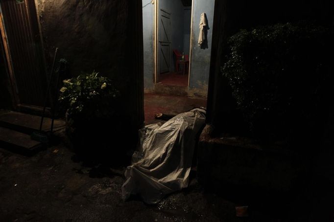 The covered-up body of a man killed in a shoot-out between members of the Mara 18 street gang and police and military during an anti-drug operation lies in a house entrance in San Pedro Sula March 27, 2013. San Pedro Sula, the country's second largest city after Tegucigalpa, has a homicide rate of 169 per 100,000 people and was named the world's most violent city for a second year in a row. Lax laws allow civilians to own up to five personal guns. Arms trafficking has flooded the country with nearly 70% illegal firearms. 83.4% of homicides are by firearms, compared to 60% in the United States. Picture taken March 27, 2013. REUTERS/Jorge Cabrera (HONDURAS - Tags: CRIME LAW CIVIL UNREST HEALTH TPX IMAGES OF THE DAY) ATTENTION EDITORS: PICTURE 38 OF 39 FOR PACKAGE 'GUN CULTURE - HONDURAS' SEARCH 'HONDURAS GUN' FOR ALL IMAGES Published: Dub. 5, 2013, 11:15 dop.