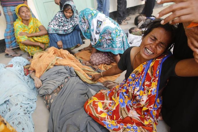 People mourn in front of the remains of their relatives, who died inside the rubble of the collapsed Rana Plaza building, in Savar, 30 km (19 miles) outside Dhaka April 25, 2013. The number of people killed by the collapse of a building in Bangladesh's capital rose to 147 overnight and the death toll could climb further because many people are still trapped inside, Dhaka's district police chief told Reuters on Thursday. REUTERS/Andrew Biraj (BANGLADESH - Tags: DISASTER TPX IMAGES OF THE DAY) Published: Dub. 25, 2013, 3:50 dop.