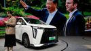 A screen shows Chinese President Xi Jinping and French President Emmanuel Macron at the GAC Motor booth while a GAC Trumpchi E9 MPV is displayed, at the Beijing Internati