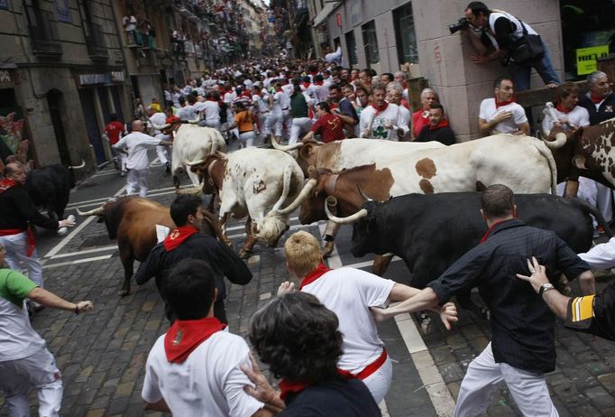 Runners sprint alongside Cebada Gago ranch fighting bulls on Santo Domingo street during the third Running Of The Bulls at the San Fermin festival in Pamplona July 9, 2012. Three people, two from Britain and one from the U.S. were gored by Fugado (Runaway), a 545 kg (1,199 pounds) bull that broke from the pack after falling in Santo Domingo in a run that lasted three minutes and thirty-eight seconds. REUTERS/Joseba Etxaburu (SPAIN - Tags: ANIMALS SOCIETY) Published: Čec. 9, 2012, 9:43 dop.