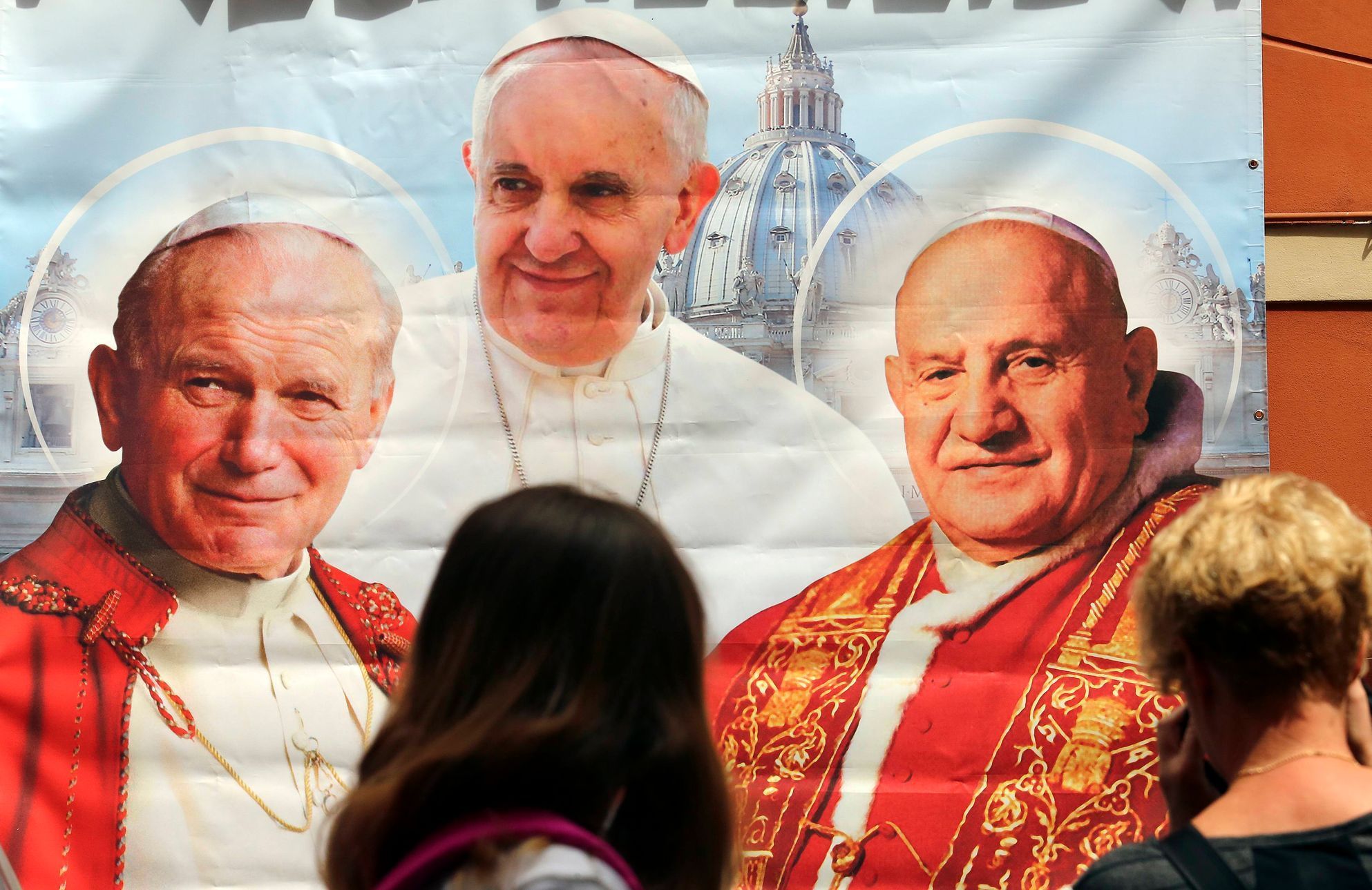 Papežové Jan Pavel II., František  a Jan XXIII. na plakátu v obchodě v Římě