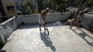 Mahesh Chaturvedi, 63 , who dresses up like Mahatma Gandhi, sweeps on the roof of his residence in the outskirts of New Delhi October 1, 2012. Chaturvedi says that the soul of Gandhi resides in him and he has been sent to continue the work of Father of the Nation. After his self proclaimed transformation in 2002 as Gandhi, Chaturvedi has been travelling extensively and plays up to his startling resemblance to Gandhi at protests and demonstrations. Picture taken October 1, 2012. REUTERS/Mansi Thapliyal (INDIA - Tags: SOCIETY) Published: Lis. 26, 2012, 3:53 dop.