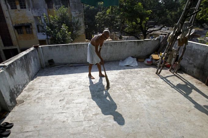 Mahesh Chaturvedi, 63 , who dresses up like Mahatma Gandhi, sweeps on the roof of his residence in the outskirts of New Delhi October 1, 2012. Chaturvedi says that the soul of Gandhi resides in him and he has been sent to continue the work of Father of the Nation. After his self proclaimed transformation in 2002 as Gandhi, Chaturvedi has been travelling extensively and plays up to his startling resemblance to Gandhi at protests and demonstrations. Picture taken October 1, 2012. REUTERS/Mansi Thapliyal (INDIA - Tags: SOCIETY) Published: Lis. 26, 2012, 3:53 dop.