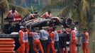 The car of Lotus Formula One driver Romain Grosjean of France is removed from the tracks during the second practice session of the Malaysian F1 Grand Prix at Sepang Inter