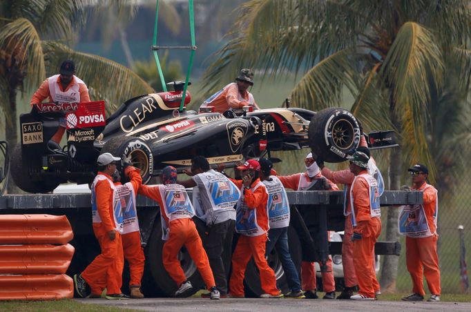 The car of Lotus Formula One driver Romain Grosjean of France is removed from the tracks during the second practice session of the Malaysian F1 Grand Prix at Sepang Inter