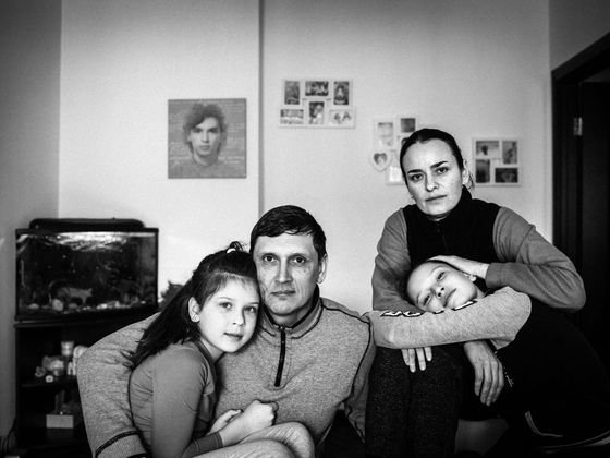 Rodina Hurykových s fotografií Romana na zdi za nimi. 