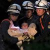 Baby is carried away by rescue workers after being rescued from her collapsed home caused by an earthquake in Mashiki town, Kumamoto prefecture, Japan