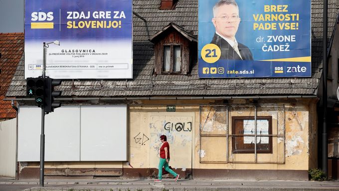 Žena prochází kolem billboardů Slovinské demokratické strany (SDS).