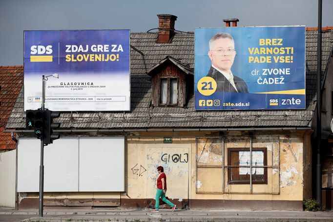 Žena prochází kolem billboardů Slovinské demokratické strany (SDS).