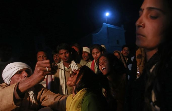 A Hindu priest offers holy water to a devotee who is believed to be possessed by evil spirits as another shouts in a state of trance at Guru Deoji Maharaj temple during a ghost fair at Malajpur village in Betul district in the central Indian state of Madhya Pradesh January 27, 2013. People from across India come to this fair to be exorcised of �evil spirits�. They are usually brought by relatives and they are most often women. The exorcism involves running around the temple courtyard to make the 'ghost' weak then being beaten by a priest with a broom. Picture taken January 27, 2013. REUTERS/Danish Siddiqui (INDIA - Tags: SOCIETY RELIGION) ATTENTION EDITORS: PICTURE 17 OF 24 FOR PACKAGE 'INDIAN GHOSTBUSTERS' SEARCH 'INDIA GHOST' FOR ALL IMAGES Published: Úno. 5, 2013, 5:10 dop.