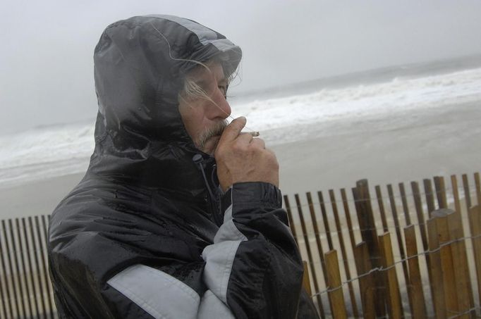 Local resident Roger Vanwart smokes a cigarette as he watches waves batter the beach at Dewey Beach, Delaware, October 29, 2012. Hurricane Sandy, the monster storm bearing down on the U.S. East Coast, strengthened on Monday after hundreds of thousands moved to higher ground, public transport shut down and the U.S. stock market suffered its first weather-related closure in 27 years. REUTERS/Jonathan Ernst (UNITED STATES - Tags: ENVIRONMENT) Published: Říj. 29, 2012, 1:57 odp.