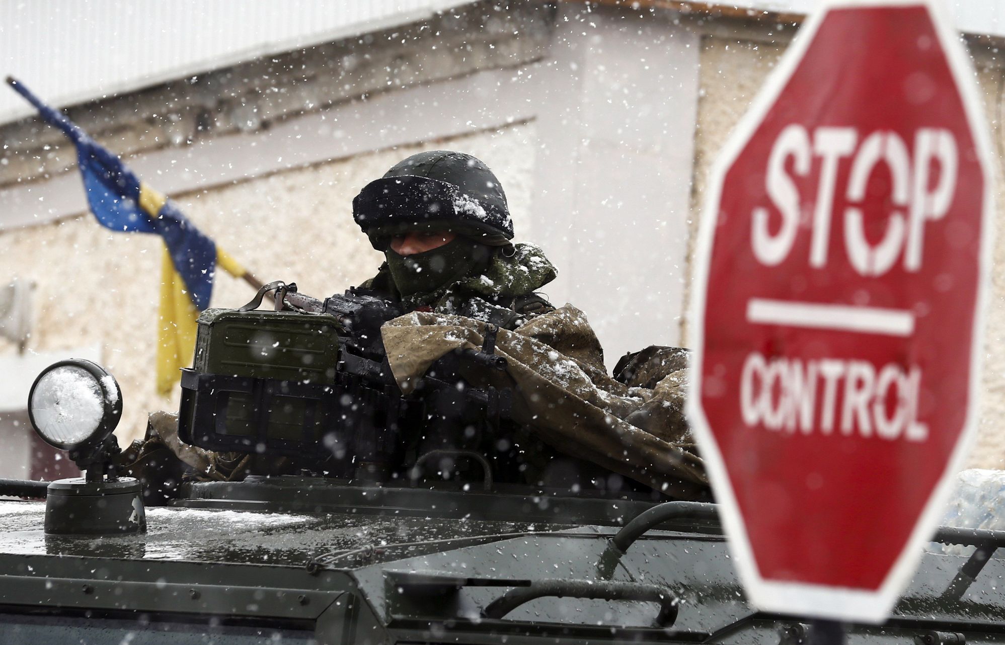 An armed man, believed to be Russian serviceman, stands guard outside a Ukrainian military base in Perevalnoye