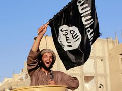 Militantní islamistický bojovník mává vlajkou ISIL na vojenské přehlídce v provincii Rákka v Sýrii.