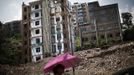 A woman walks pass a building under demolition at a residential area which will be relocated, in Huangtupo, Badong city, 100km (62 miles) from the Three Gorges dam in Hubei province in this August 8, 2012 file photo. China relocated 1.3 million people during the 17 years it took to complete the Three Gorges dam. Even after finishing the $59 billion project last month, the threat of landslides along the dam's banks will force tens of thousands to move again. It's a reminder of the social and environmental challenges that have dogged the world's largest hydroelectric project. While there has been little protest among residents who will be relocated a second time, the environmental fallout over other big investments in China has become a hot-button issue ahead of a leadership transition this year. Picture taken on August 8, 2012. To match story CHINA-THREEGORGES/ REUTERS/Carlos Barria/Files (CHINA - Tags: POLITICS ENVIRONMENT BUSINESS ENERGY) Published: Srp. 22, 2012, 8:33 odp.