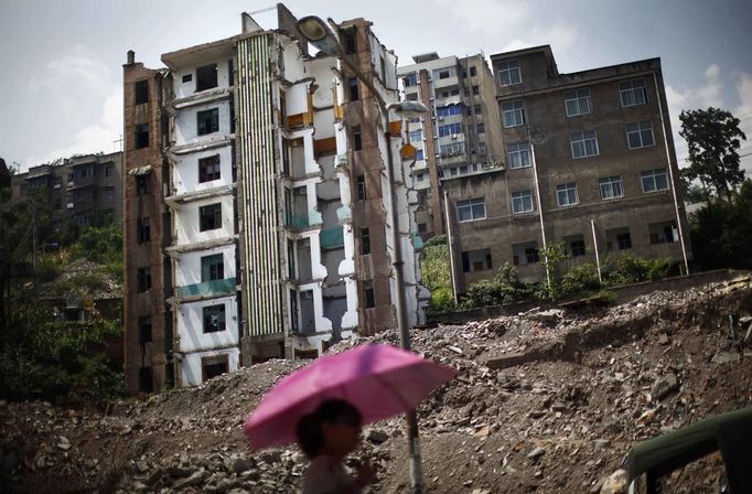 A woman walks pass a building under demolition at a residential area which will be relocated, in Huangtupo, Badong city, 100km (62 miles) from the Three Gorges dam in Hubei province in this August 8, 2012 file photo. China relocated 1.3 million people during the 17 years it took to complete the Three Gorges dam. Even after finishing the $59 billion project last month, the threat of landslides along the dam's banks will force tens of thousands to move again. It's a reminder of the social and environmental challenges that have dogged the world's largest hydroelectric project. While there has been little protest among residents who will be relocated a second time, the environmental fallout over other big investments in China has become a hot-button issue ahead of a leadership transition this year. Picture taken on August 8, 2012. To match story CHINA-THREEGORGES/ REUTERS/Carlos Barria/Files (CHINA - Tags: POLITICS ENVIRONMENT BUSINESS ENERGY) Published: Srp. 22, 2012, 8:33 odp.