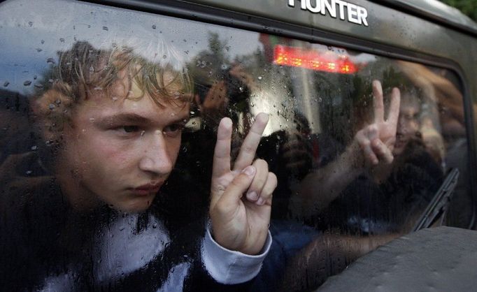 Gesto zadrženého muže sedícího v policejním autě v centru Minsku (29. června). Kolem tisícovky lidí se sešlo 29. června na demonstraci internetové skupiny s názvem "Revoluce přes sociální sítě". Skupina však byla rozehnána policií a řada lidí zadržena.