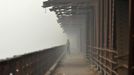 A man walks over a bridge built over the Yamuna river amid dense smog in Delhi November 8, 2012. Indians are at high risk of respiratory ailments, heart disease and lung cancer, according to World Health Organization (WHO) data that showed Delhi's air had almost 10 times the recommended level of PM10 particulate matter, or particles small enough to penetrate to the deepest part of the lungs and cause health problems. REUTERS/Mansi Thapliyal (INDIA - Tags: ENVIRONMENT SOCIETY HEALTH) Published: Lis. 8, 2012, 10:13 dop.