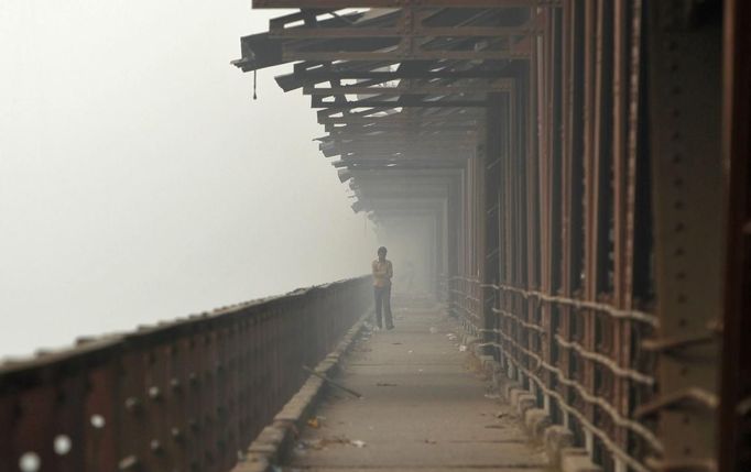 A man walks over a bridge built over the Yamuna river amid dense smog in Delhi November 8, 2012. Indians are at high risk of respiratory ailments, heart disease and lung cancer, according to World Health Organization (WHO) data that showed Delhi's air had almost 10 times the recommended level of PM10 particulate matter, or particles small enough to penetrate to the deepest part of the lungs and cause health problems. REUTERS/Mansi Thapliyal (INDIA - Tags: ENVIRONMENT SOCIETY HEALTH) Published: Lis. 8, 2012, 10:13 dop.