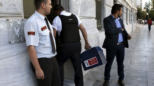 Ostraha vnáší hotovost do pobočky Řecké národní banky.
