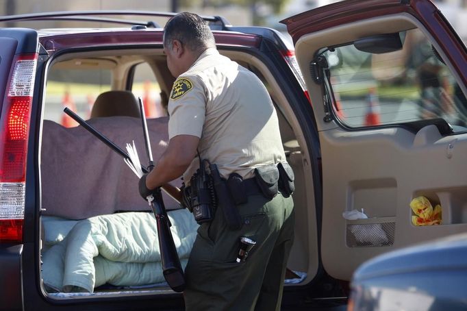 A Los Angeles County Sheriff's deputy takes in guns from motorists trading them in at the 'Gifts for Guns' gun buyback in Compton, California, January 21, 2013. People can trade in their guns anonymously and with no questions asked in exchange for $200 gift cards for assault weapons, $100 gift cards for shotguns, handguns and rifles, and $50 for non-operational firearms. U.S. President Barack Obama is pushing to address controversial issues surrounding gun violence and regulation as he begins his second term in office. REUTERS/David McNew (UNITED STATES - Tags: POLITICS SOCIETY) Published: Led. 21, 2013, 10:52 odp.