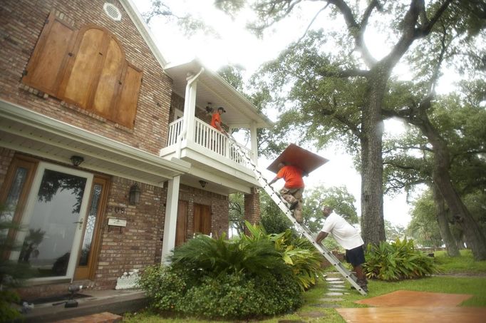 Jason Preston, Jermaine McNair and James Hayes put up shutters on a house as Hurricane Isaac approaches Gulfport, Mississippi, August 28, 2012. Photo taken August 28, 2012. REUTERS/Michael Spooneybarger (UNITED STATES - Tags: ENVIRONMENT DISASTER) Published: Srp. 29, 2012, 11:18 dop.