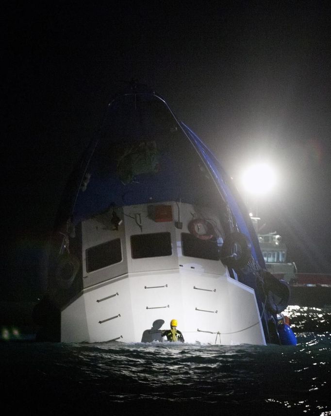 : A rescuer checks a partially submerged boat after two vessels collided in Hong Kong October 1, 2012. A major rescue is underway in the waters near Yung Shue Wan on Hong Kong's Lamma island following a collision involving two vessels in the evening, government radio reported on Monday. Police say there were about 100 people onboard both vessels, with many of them in the water. The government says 101 people have been rescued so far with at least 25 hospitalised. REUTERS/Tyrone Siu (CHINA - Tags: DISASTER TRANSPORT) Published: Říj. 1, 2012, 4:32 odp.