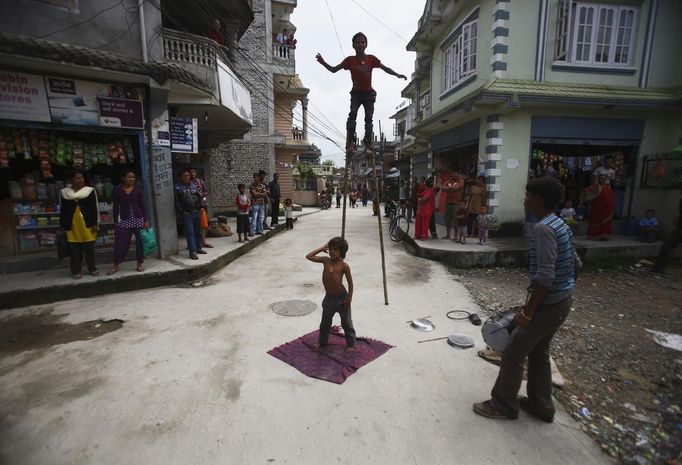 Gchan Choudhary, 17, (R) plays a drum as his siblings Drumpal, 11, and Shivani, 7, perform on a street in Kathmandu August 15, 2012. The siblings, who came to Kathmandu from India 5 years ago, earn their living by performing tricks on the streets of Kathmandu. According to Drumpal they earn around $10 a day by performing tricks, which is not enough to feed their 10-member family living together in a small hut without a proper toilet or any basic needs. REUTERS/Navesh Chitrakar (NEPAL - Tags: SOCIETY IMMIGRATION POVERTY) Published: Srp. 15, 2012, 4:34 odp.