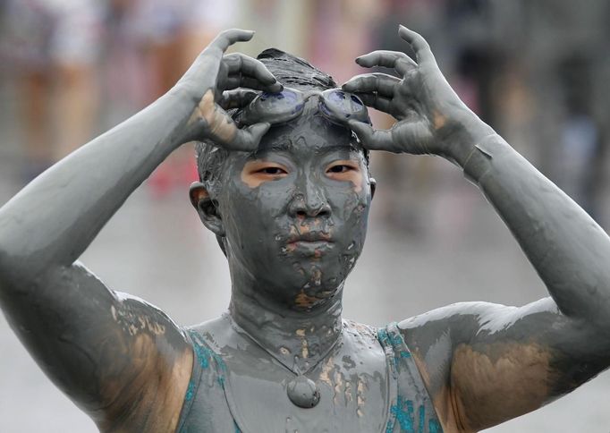 A woman takes off her goggles at the Boryeong Mud Festival on Daecheon beach in Boryeong, about 190 km (118 miles) southwest of Seoul, July 15, 2012. About 2 to 3 million domestic and international tourists visit the beach during the annual mud festival, according to the festival organisation. REUTERS/Lee Jae-Won (SOUTH KOREA - Tags: SOCIETY TRAVEL) Published: Čec. 15, 2012, 6:57 dop.