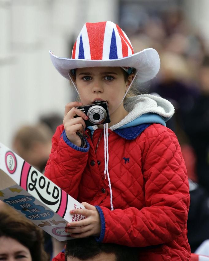 A girl wearing a Union flag-themed hat gets ready to take a picture, while waiting in the crowd along Parliament Square to see the Queen in London June 5, 2012. Four days of nationwide celebrations during which millions of people have turned out to mark the Queen's Diamond Jubilee conclude on Tuesday with a church service and carriage procession through central London. REUTERS/Kevin Coombs (BRITAIN - Tags: SOCIETY ROYALS) Published: Čer. 5, 2012, 1:32 odp.