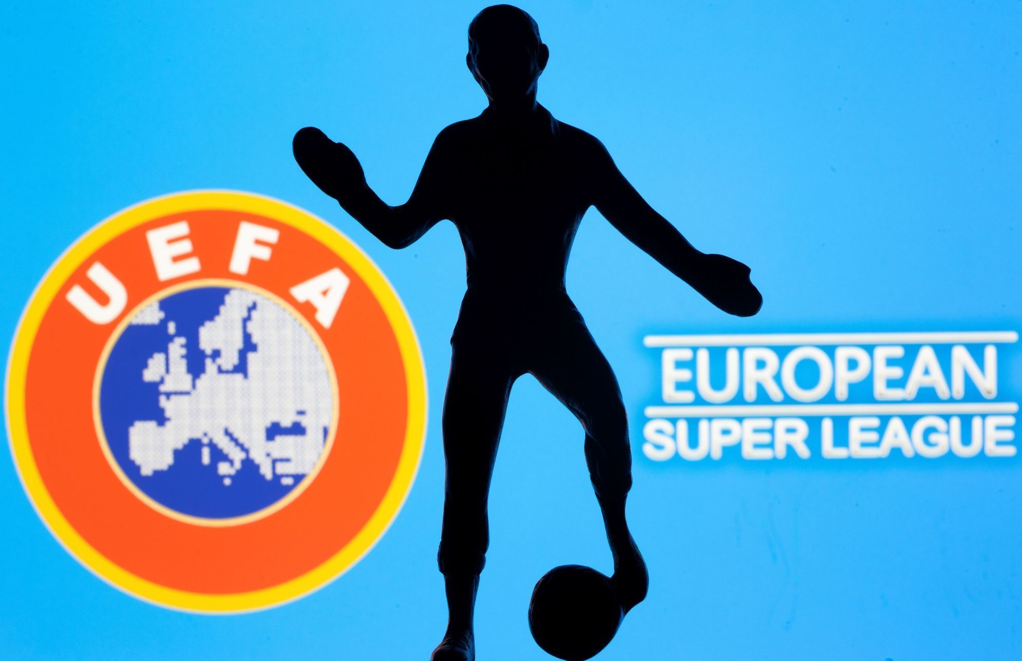 A metal figure of a football player with a ball is seen in front of the words "European Super League" and the UEFA logo in this illustration