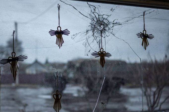 Angel figurines are seen on a window of a local grocery store broken by shrapnel while a Ukrainian Army truck moves past in a village near a frontline, amid Russia's atta