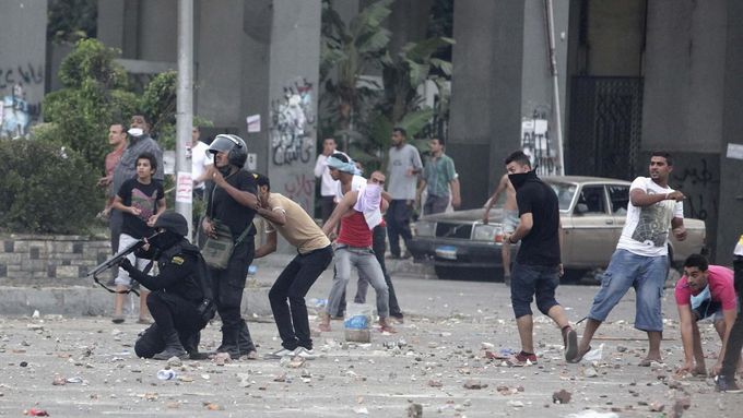 Policista míří pistolí na příznivce svrženého egyptského prezidenta Mursího během sobotních střetů ve městě Nasr, západně od Káhiry.