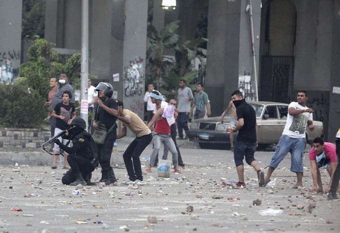 Policista míří pistolí na příznivce svrženého egyptského prezidenta Mursího během sobotních střetů ve městě Nasr, západně od Káhiry.