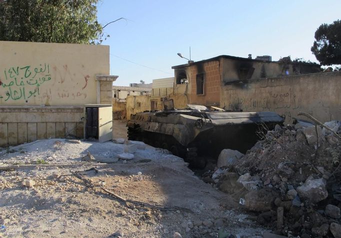 A damaged tank that belonged to government forces is seen in the town of Atareb in the Syrian province of Aleppo, in an area now held by Syrian rebels, July 3, 2012. The graffiti on the wall (R) reads "Al-Assad is staying forever". Picture taken July 3, 2012. REUTERS/Stringer (SYRIA - Tags: POLITICS CIVIL UNREST MILITARY) Published: Čec. 4, 2012, 10:12 dop.