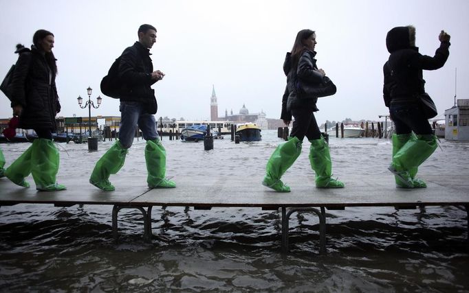 Tourists walk on raised platforms for flood waters in St. Mark Square during a period of seasonal high water in Venice October 27, 2012. The water level in the canal city rose to 127 cm (50 inches) above the normal level, according to the monitoring institute. REUTERS/Manuel Silvestri (ITALY - Tags: ENVIRONMENT SOCIETY TRAVEL) Published: Říj. 27, 2012, 12:09 odp.